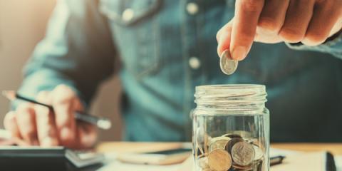 Individual dropping a coin into jar