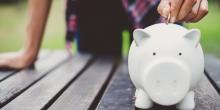 child putting coin in piggy bank